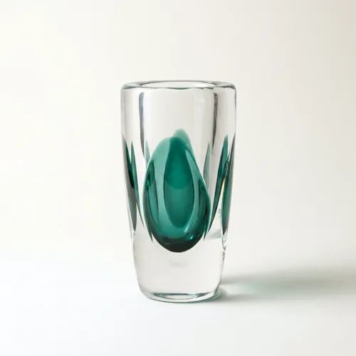 A clear cased glass vase with a deep green teardrop suspended inside it